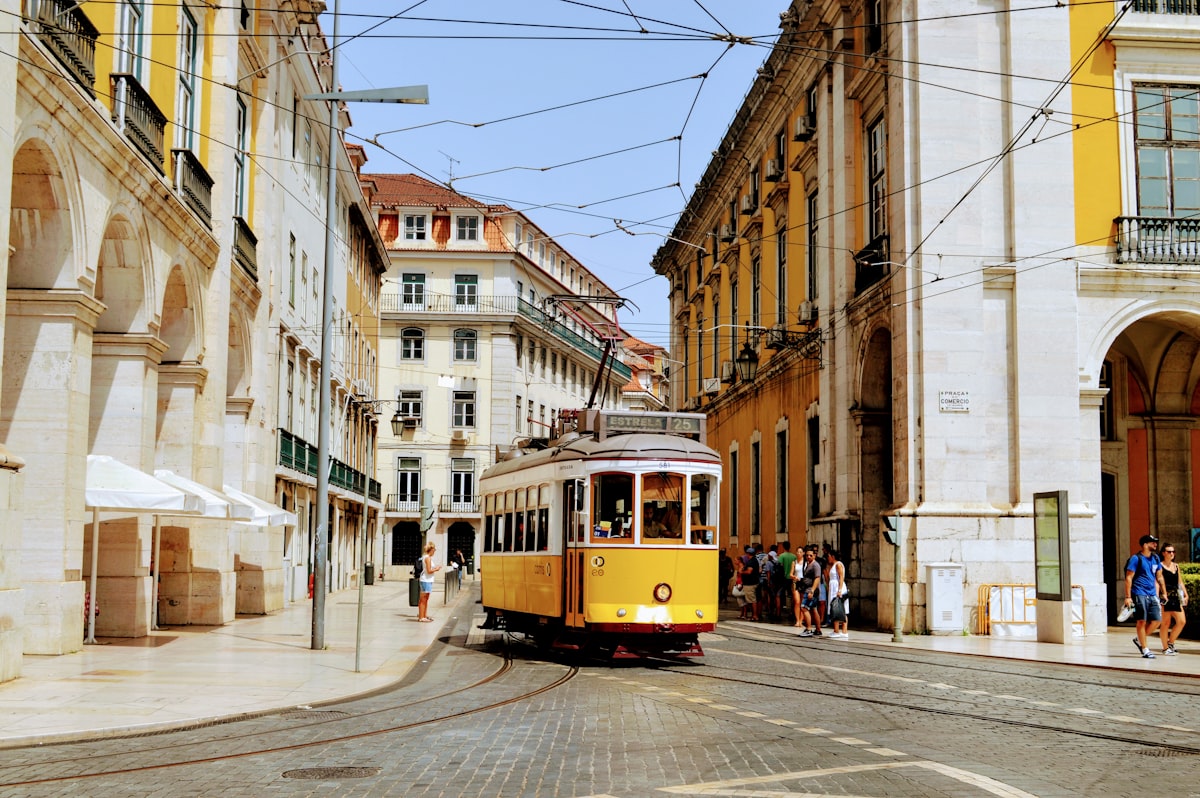 Traditional yellow tram on a narrow Lisbon street lined with colorful buildings